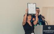 A woman holds up a whiteboard with a design.